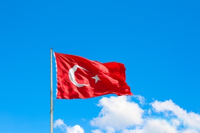 Photo of Turkish flag fluttering on blue sky background