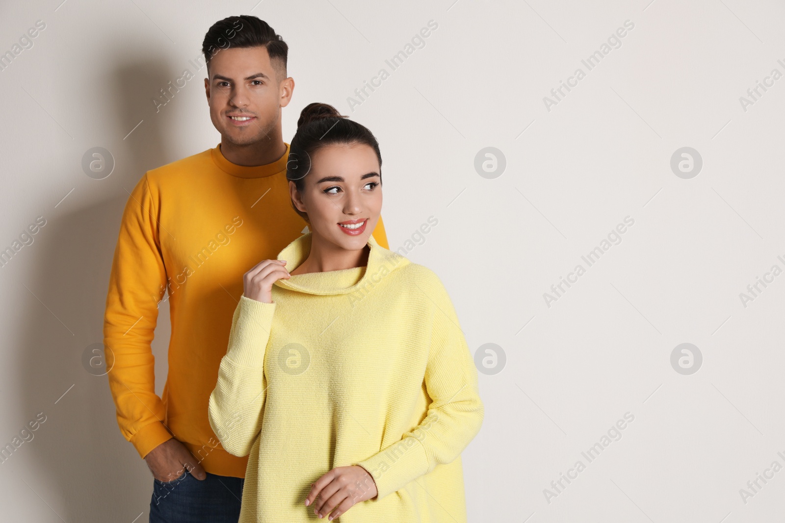 Photo of Happy couple wearing yellow warm sweaters on white background. Space for text