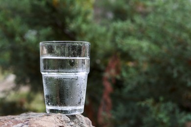 Glass of water on stone outdoors, space for text