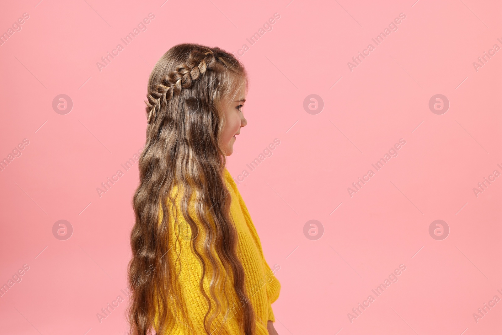 Photo of Cute little girl with braided hair on pink background. Space for text