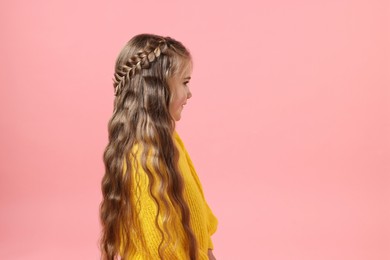 Photo of Cute little girl with braided hair on pink background. Space for text