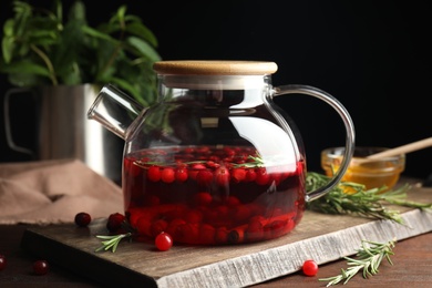 Tasty hot cranberry tea and fresh ingredients on wooden table