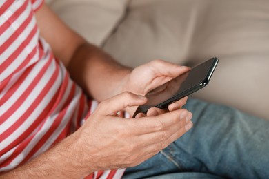 Photo of Man using smartphone at home, closeup view