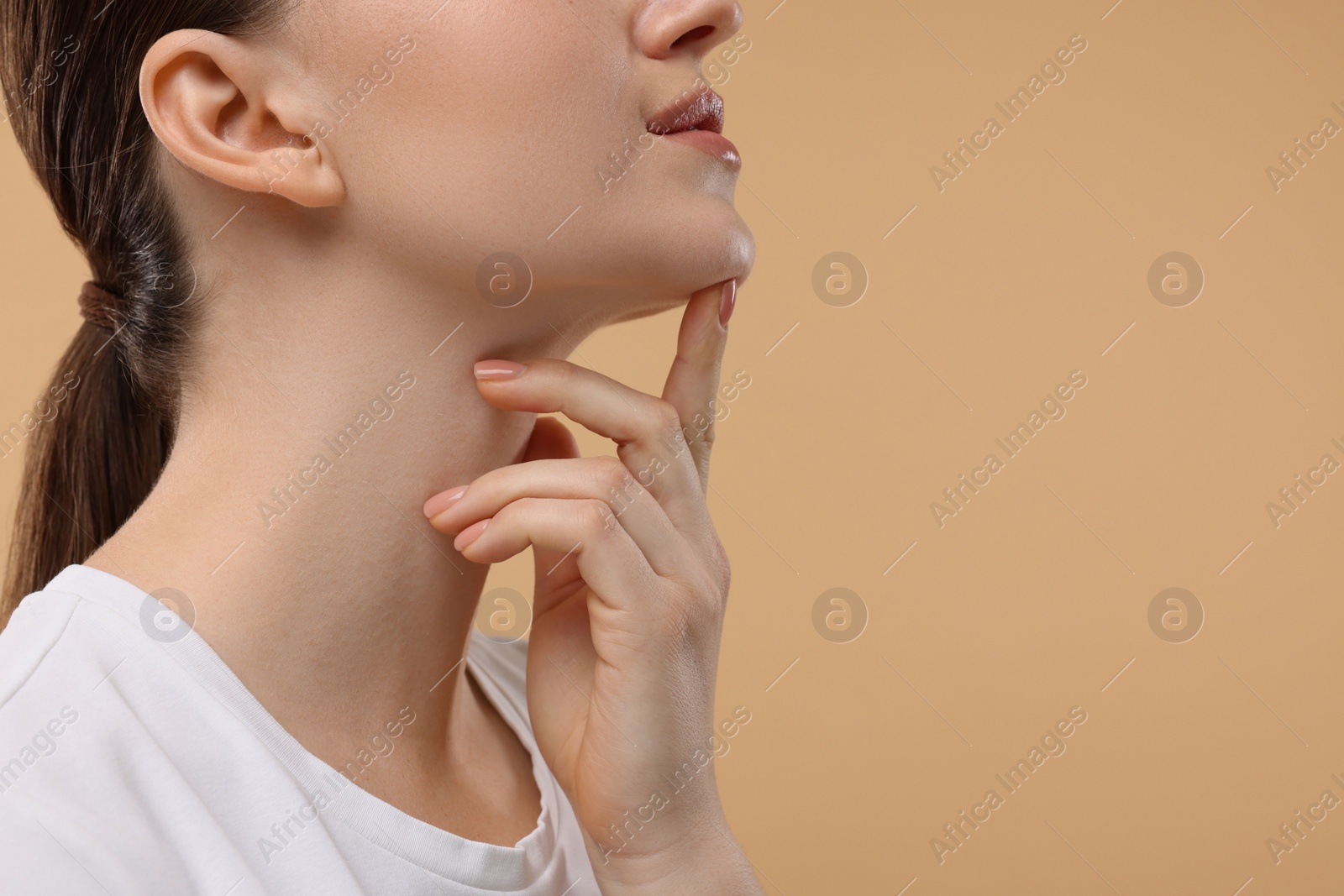 Photo of Woman touching her chin on beige background, closeup. Space for text