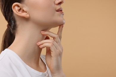 Photo of Woman touching her chin on beige background, closeup. Space for text