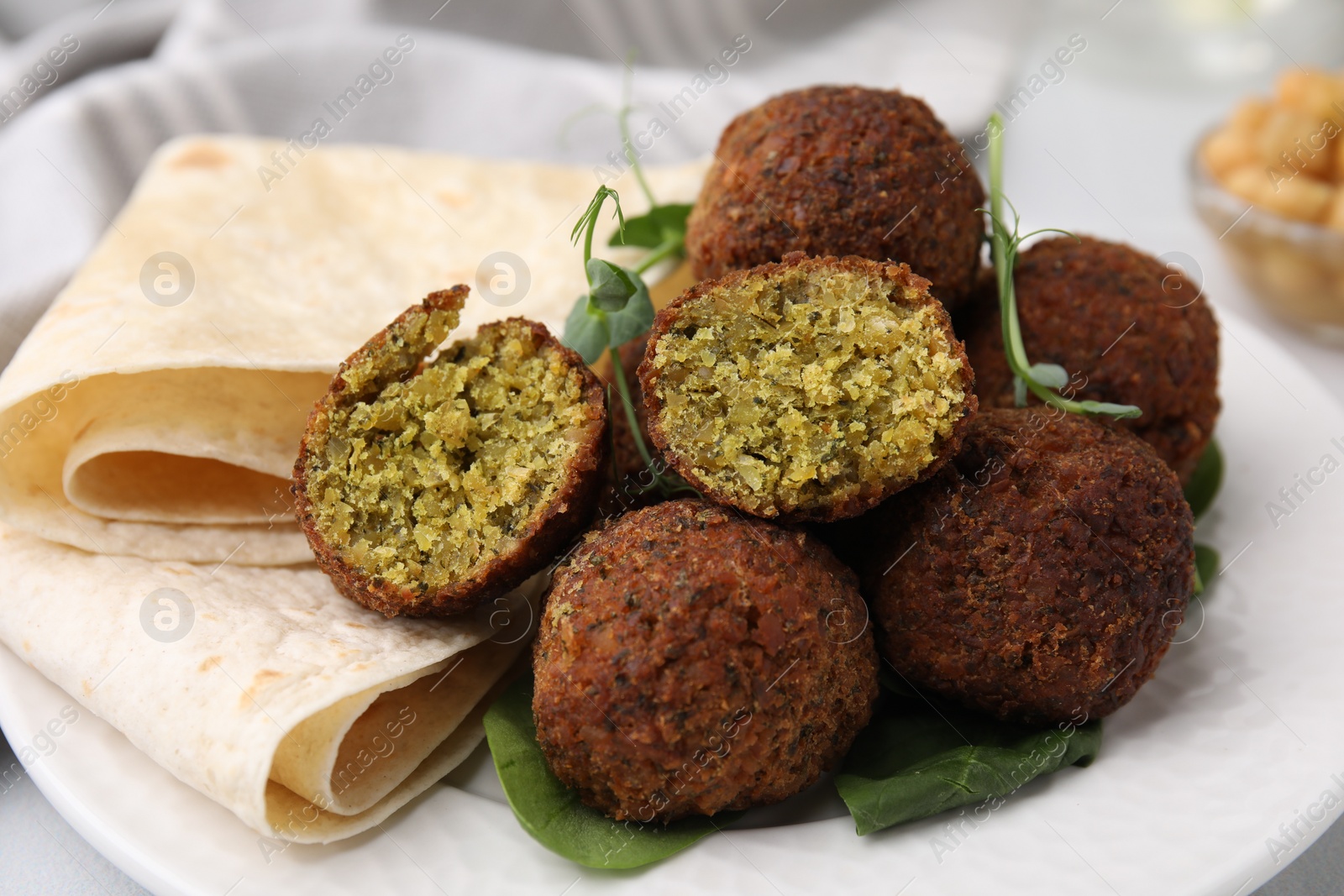 Photo of Delicious falafel balls, herbs and lavash on plate, closeup