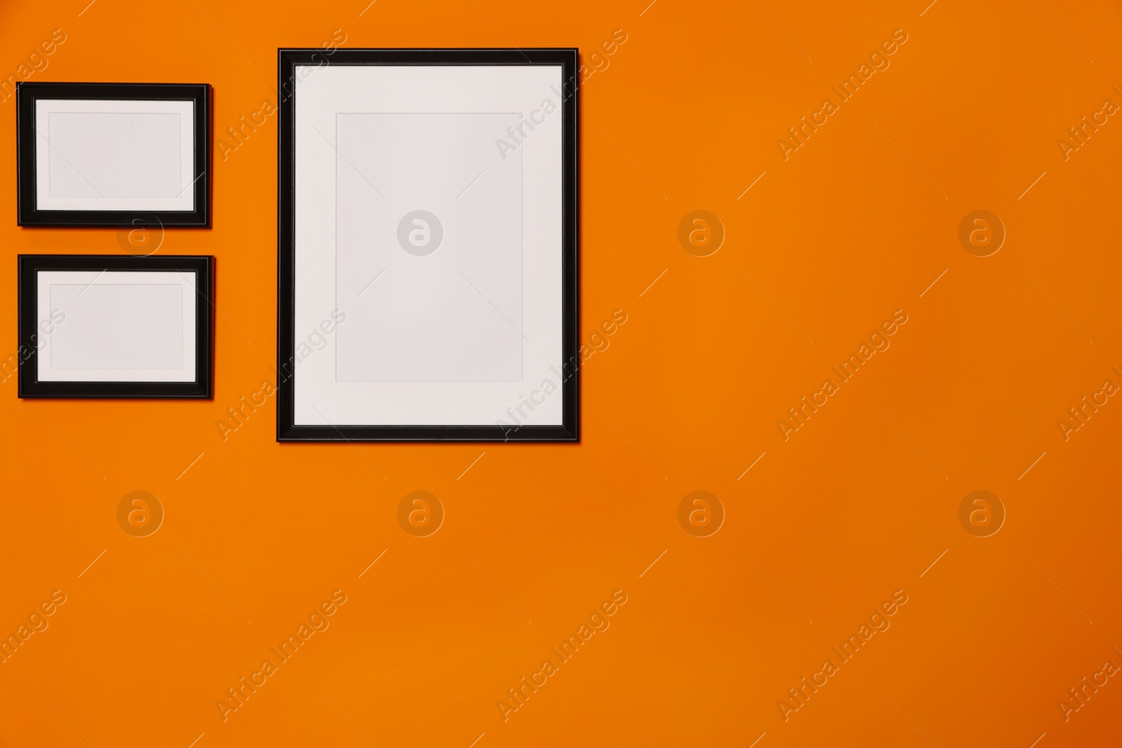 Photo of Empty frames hanging on orange wall. Mockup for design