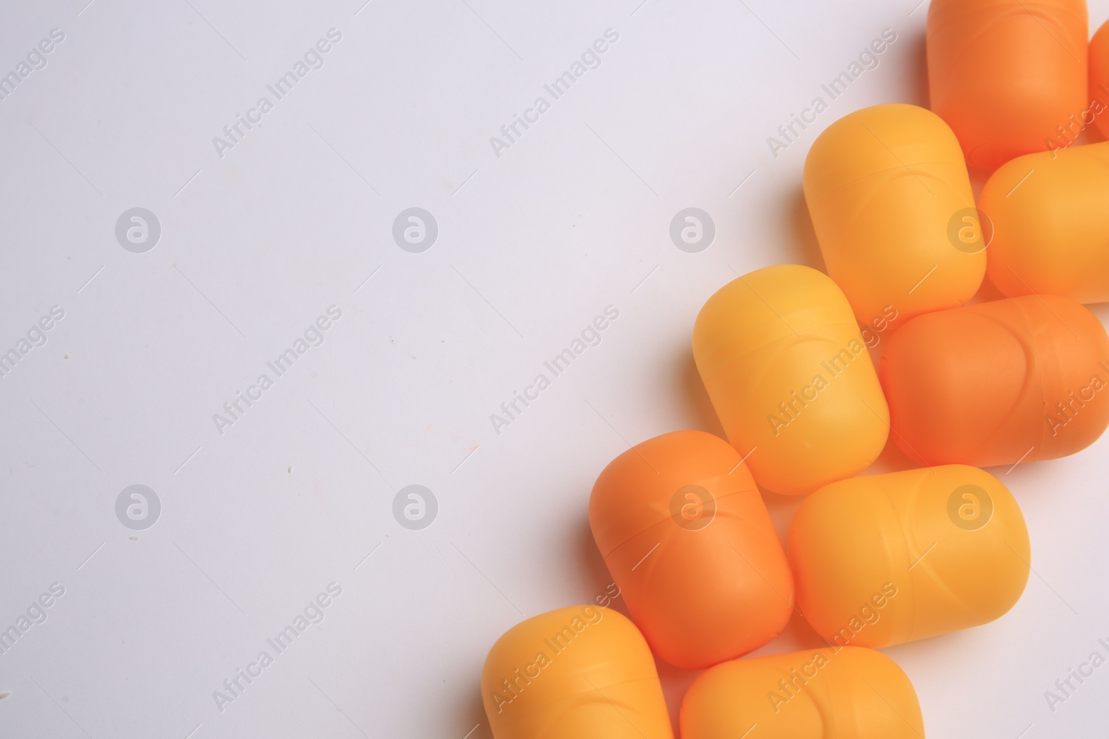 Photo of Sveti Vlas, Bulgaria - June 30, , 2023: Orange plastic capsules from Kinder Surprise Eggs on white background, flat lay and space for text