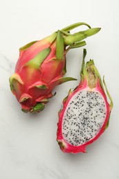 Photo of Delicious cut and whole dragon fruits (pitahaya) on white table, flat lay
