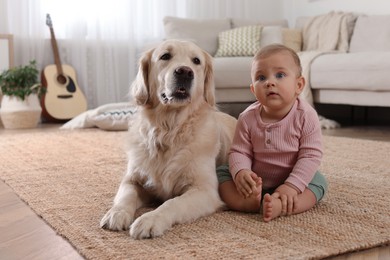 Cute little baby with adorable dog on floor at home