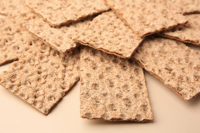 Photo of Fresh crunchy crispbreads on beige background, closeup