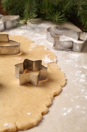 Photo of Making Christmas cookies. Raw dough and metal cutters on table, closeup