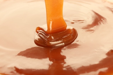 Photo of Pouring delicious caramel sauce as background, closeup