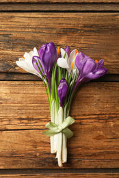 Beautiful spring crocus flowers on wooden table, top view