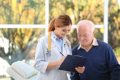 Doctor working with elderly patient in hospital. Space for text