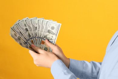 Photo of Woman holding dollar banknotes on yellow background, closeup. Money exchange concept