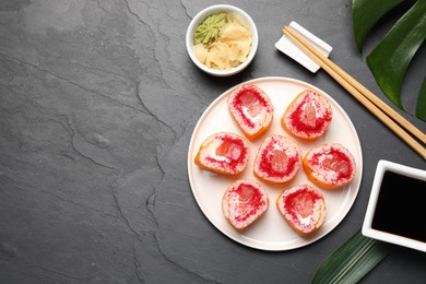 Flat lay composition with sushi rolls on black textured table. Space for text