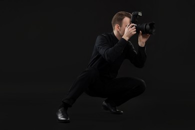 Photo of Professional photographer taking picture on black background