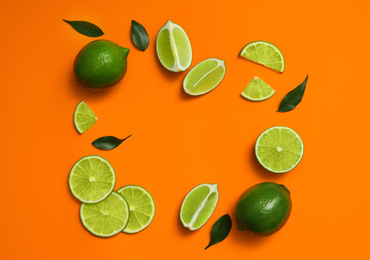 Photo of Flat lay composition with fresh juicy limes on orange background. Space for text