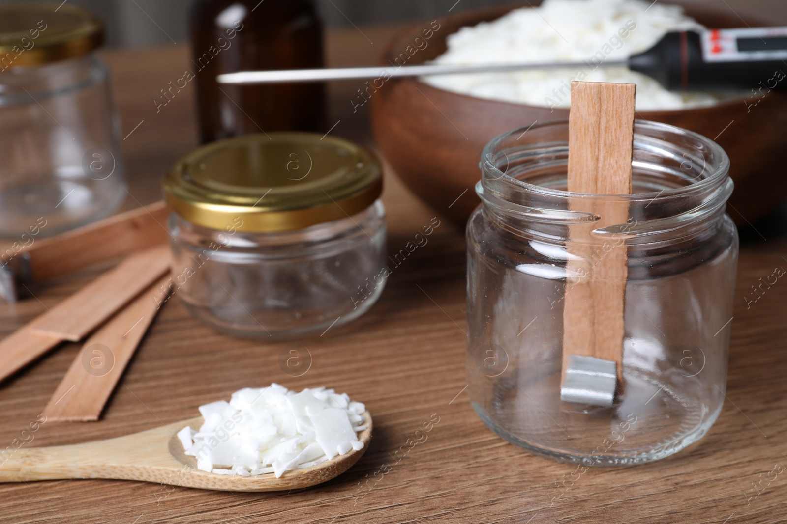 Photo of Glass jar with wick and wax flakes on wooden table. Making homemade candle