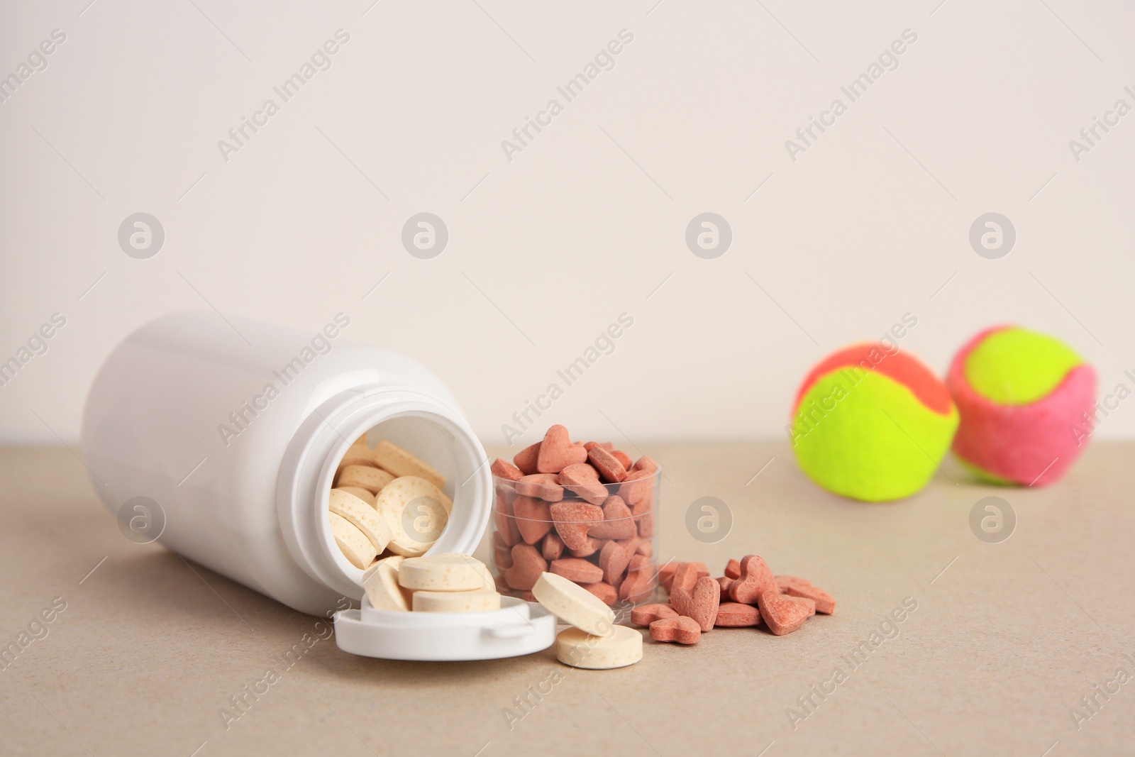 Photo of Different pet vitamins and toy balls on beige table, space for text