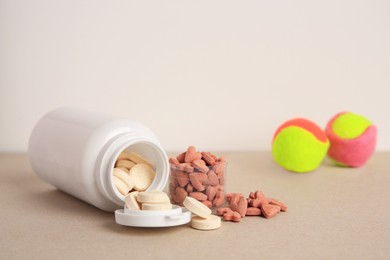 Different pet vitamins and toy balls on beige table, space for text