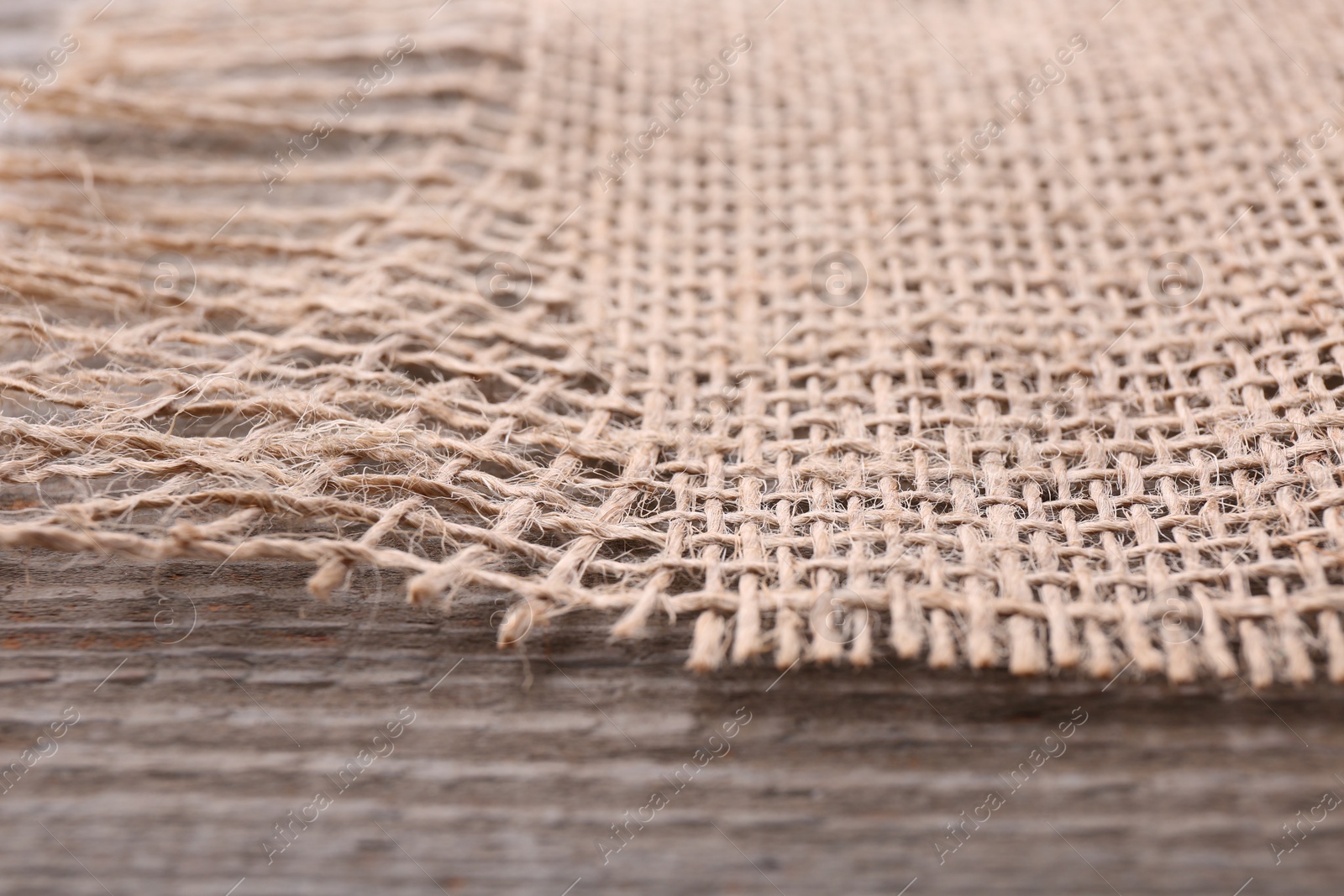 Photo of Piece of burlap fabric on wooden table, closeup