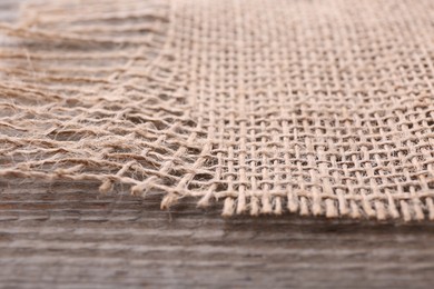 Piece of burlap fabric on wooden table, closeup