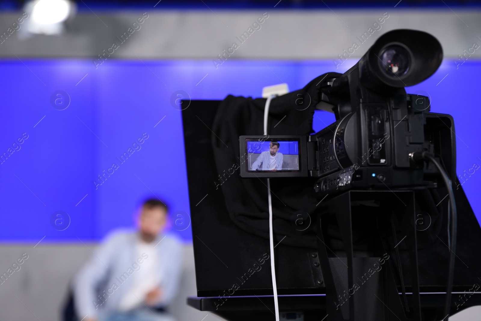 Photo of Presenter working in studio, focus on video camera