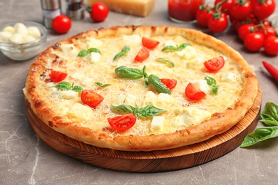 Photo of Delicious pizza with cheese, basil and tomatoes on table