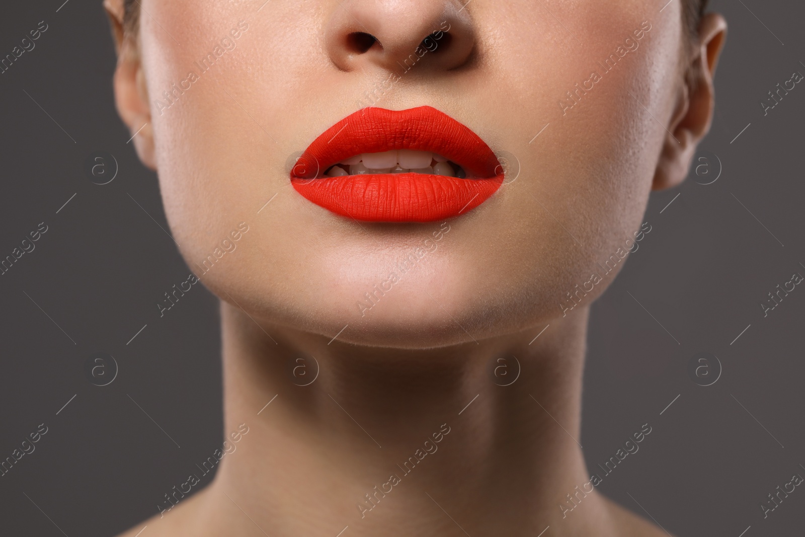 Photo of Young woman with beautiful red lips on grey background, closeup