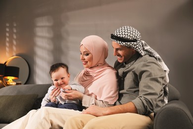 Photo of Happy Muslim family with little son in living room