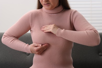 Photo of Mammology. Woman doing breast self-examination indoors, closeup