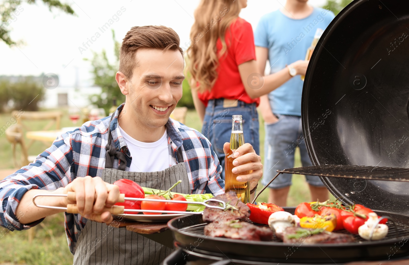 Photo of Man cooking meat and vegetables on barbecue grill outdoors