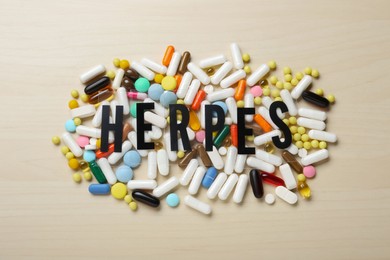 Word Herpes and different pills on wooden table, flat lay