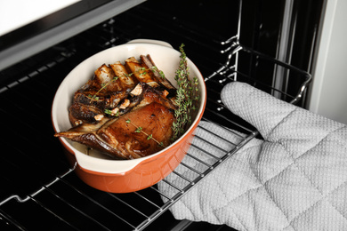 Chef taking delicious roasted ribs out of oven, closeup