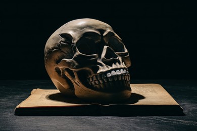 Photo of Human skull on old book against black background