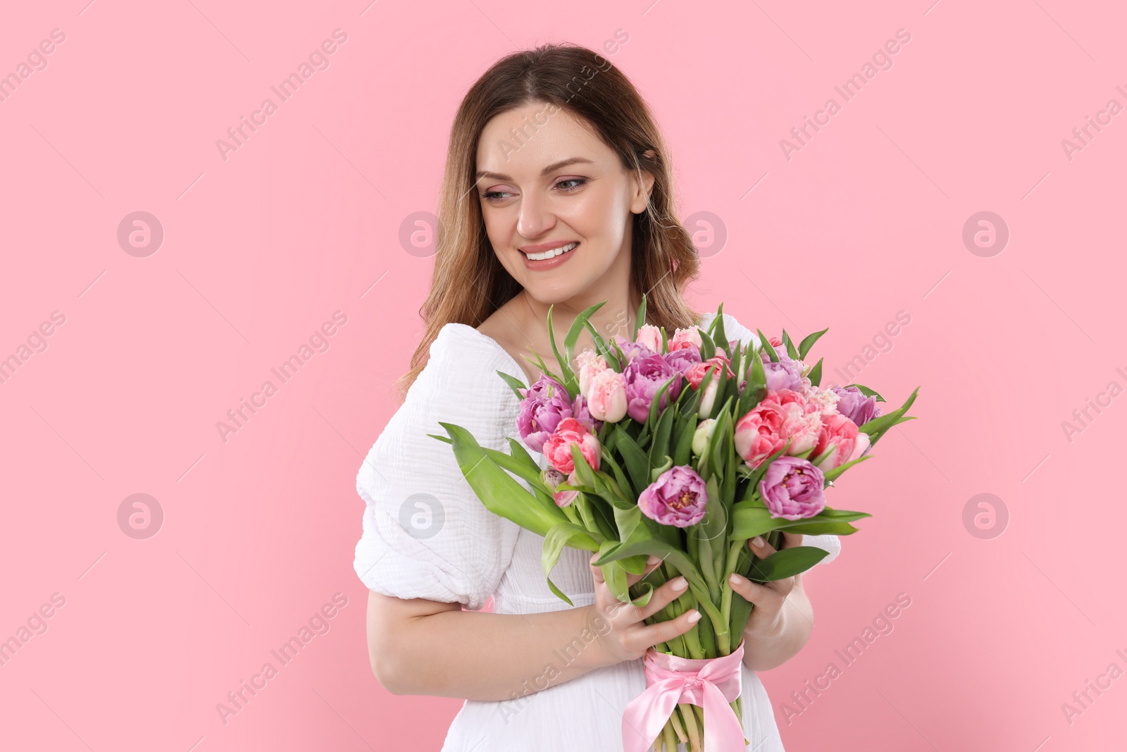 Photo of Happy young woman with bouquet of beautiful tulips on pink background