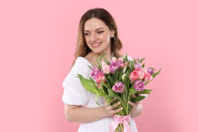 Photo of Happy young woman with bouquet of beautiful tulips on pink background