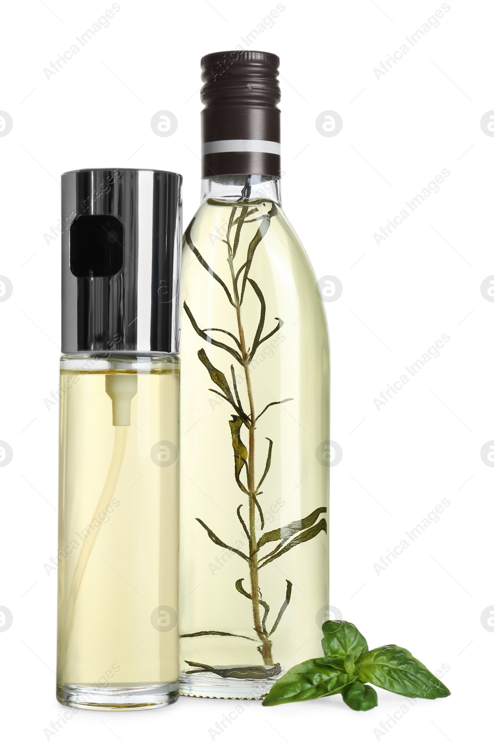 Photo of Bottles of cooking oil and basil leaves on white background