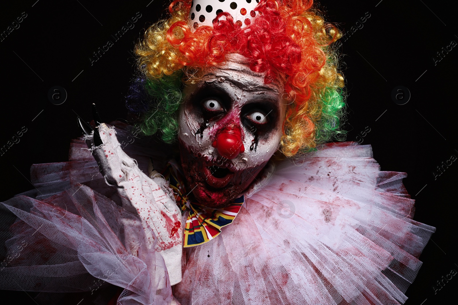 Photo of Terrifying clown on black background. Halloween party costume