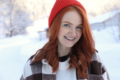 Portrait of beautiful young woman on snowy day outdoors. Winter vacation