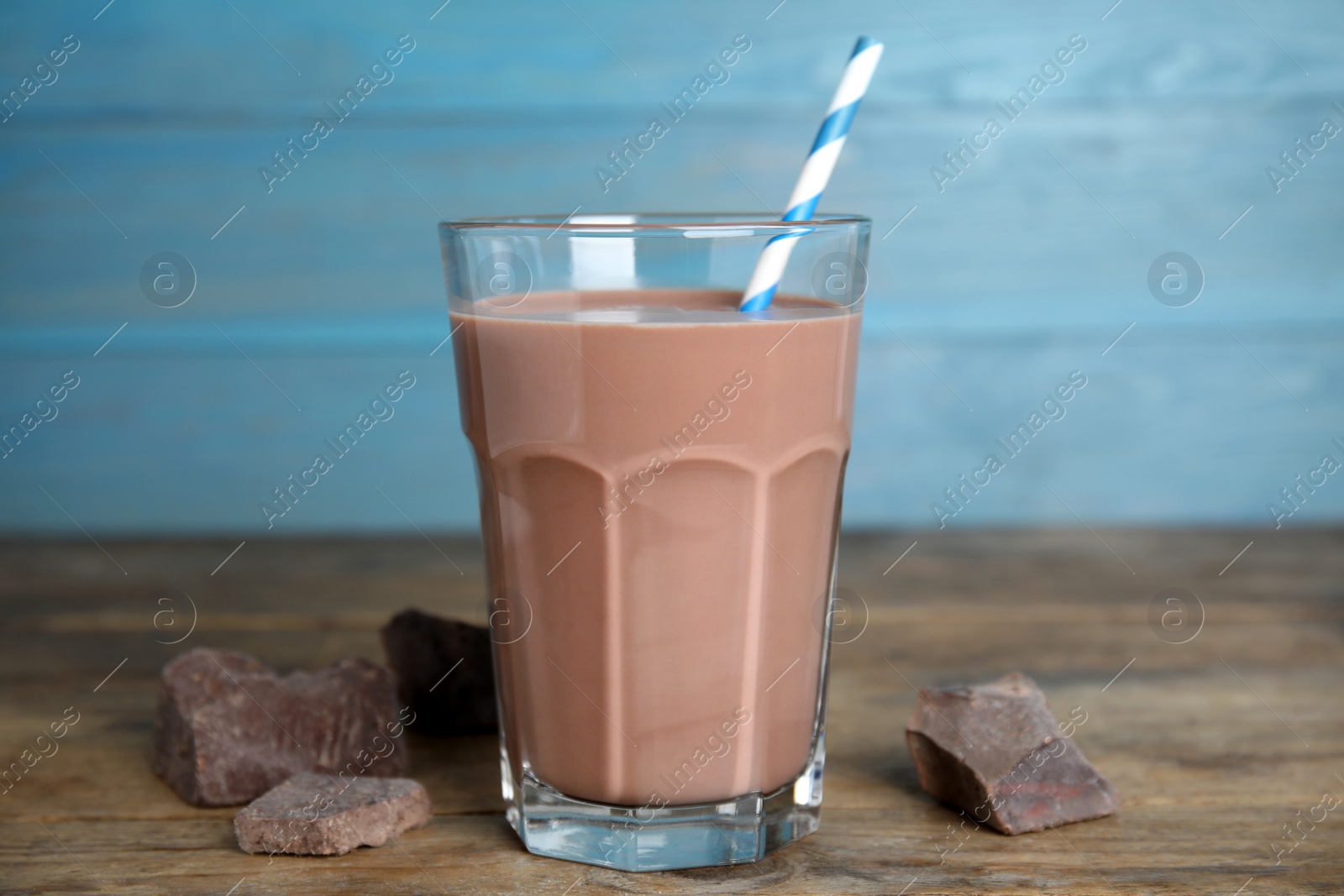 Photo of Delicious chocolate milk in glass on wooden table