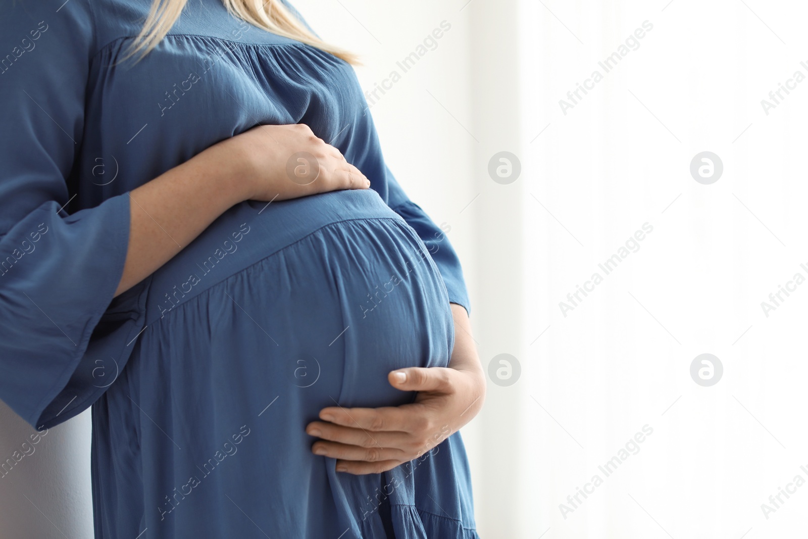 Photo of Pregnant woman on light background, closeup. Space for text