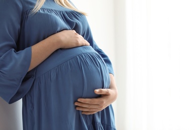 Pregnant woman on light background, closeup. Space for text