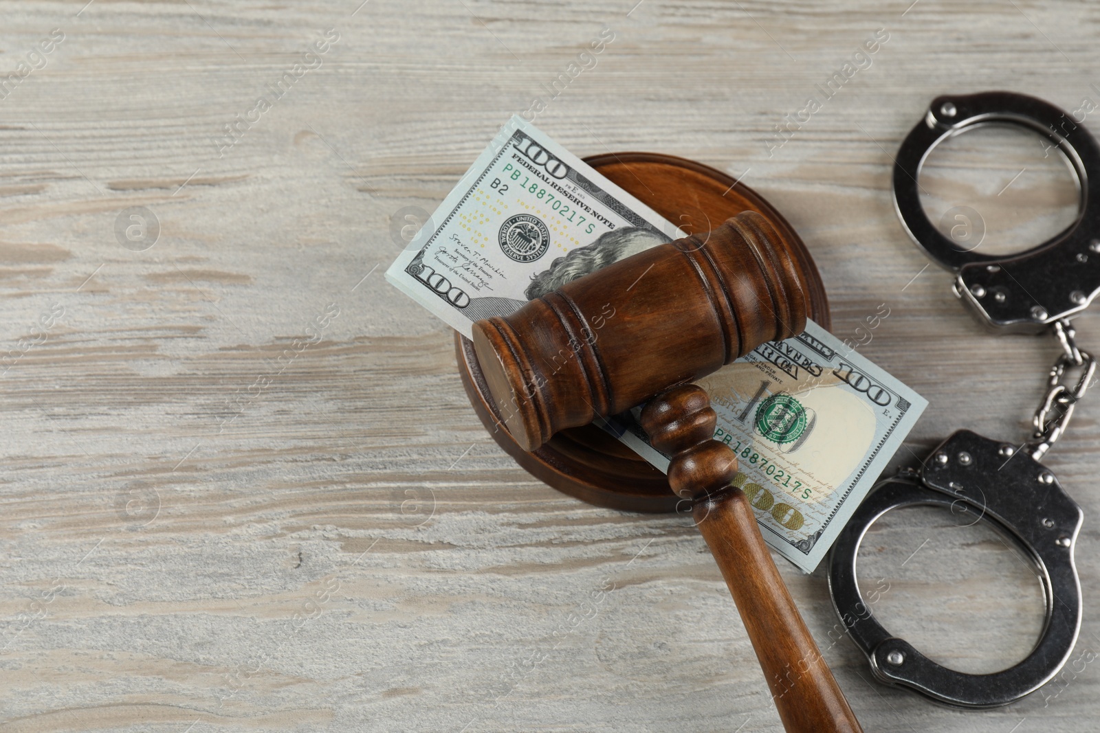 Photo of Judge's gavel, money and handcuffs on wooden table, flat lay. Space for text