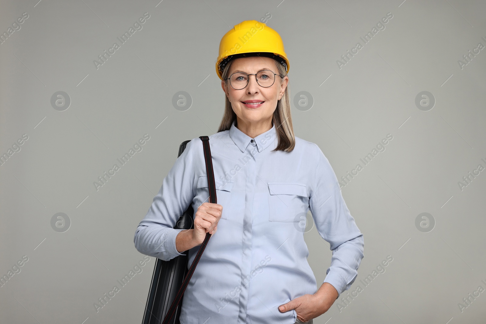 Photo of Architect in hard hat with tube on grey background