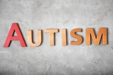 Photo of Word AUTISM on grey background, top view