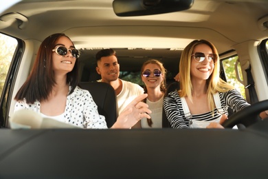 Happy friends with map in car on road trip