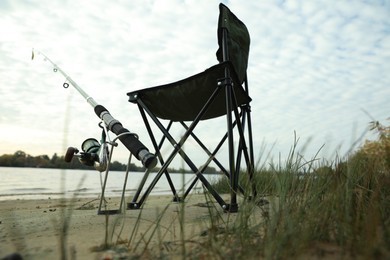 Photo of Folding chair and fishing rod at riverside, low angle view